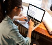 Young female blogger working at home.She sitting in her working room and typing something on laptop.